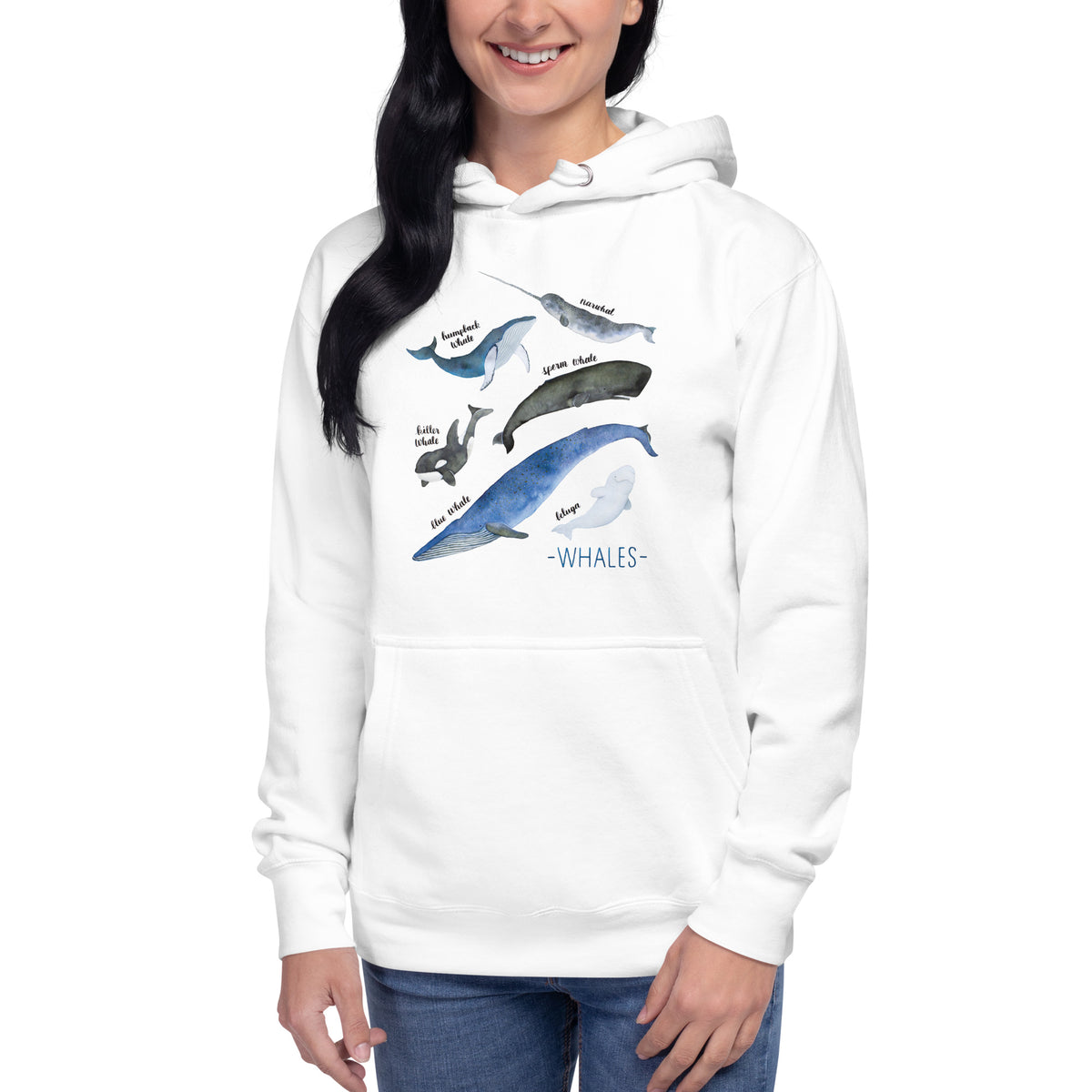 A woman wearing a white pullover hoodie with a watercolor-style whale graphic on the front, paired with blue jeans, against a plain white background.
